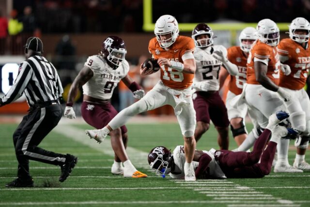 O quarterback do Texas Longhorns, Arch Manning, corre para um touchdown com um jogador do Texas A&M Aggies no chão.