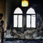 Um homem palestino segura um fragmento chamuscado de uma página do Alcorão dentro da Mesquita Hajja Hamida depois de ter sido incendiada e vandalizada por colonos israelenses na aldeia palestina de Deir Istiya, perto de Salfit, na Cisjordânia ocupada por Israel, em 13 de novembro de 2025.