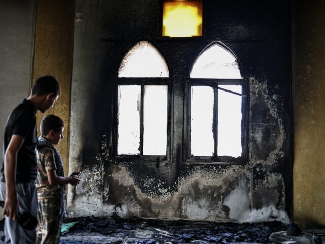 Um homem palestino segura um fragmento chamuscado de uma página do Alcorão dentro da Mesquita Hajja Hamida depois de ter sido incendiada e vandalizada por colonos israelenses na aldeia palestina de Deir Istiya, perto de Salfit, na Cisjordânia ocupada por Israel, em 13 de novembro de 2025.