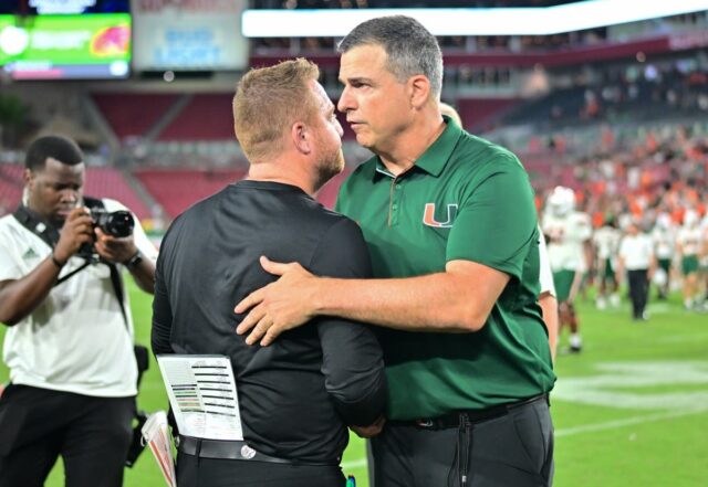 College football head coach Mario Cristobal of the Miami Hurricanes shakes hands with head coach Alex Golesh