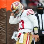 O quarterback do San Francisco 49ers, Brock Purdy (13), é derrubado pelo lado defensivo do Cleveland Browns, Myles Garrett (95), durante um jogo de futebol americano da NFL, domingo, 30 de novembro de 2025, em Cleveland. (Foto AP/Kirk Irwin)
