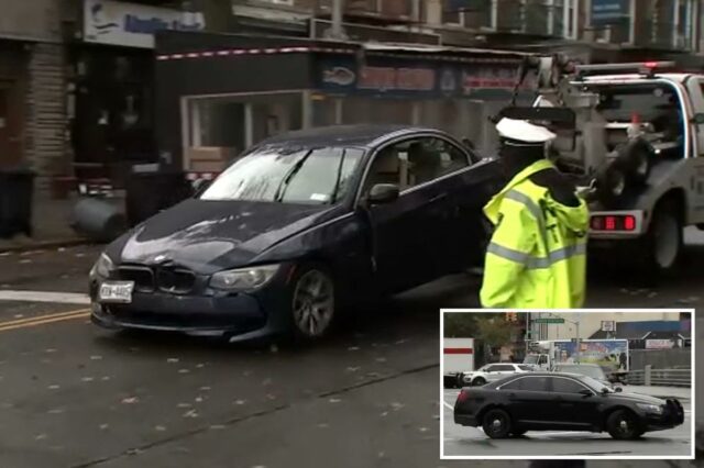 Um carro escuro danificado sendo rebocado em uma rua da cidade.