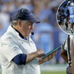 O técnico da Carolina do Norte, Bill Belichick, verificando seu tablet durante um jogo de futebol.