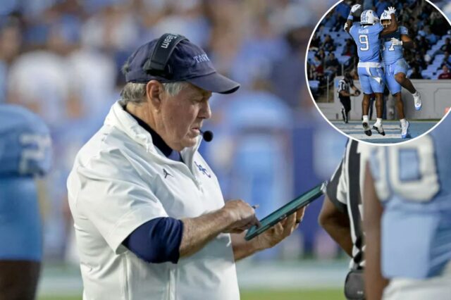 O técnico da Carolina do Norte, Bill Belichick, verificando seu tablet durante um jogo de futebol.