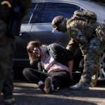 Um manifestante fantasiado de sapo inflável se aproxima de um policial durante um protesto em frente ao escritório do Departamento de Segurança Interna