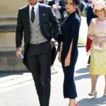 O Daily Mail pode revelar que Victoria Beckham fez para o marido o terno que ele usará ao ser homenageado por seus serviços ao esporte e à caridade. Na foto: David Beckham e Victoria Beckham chegam à Capela de São Jorge no Castelo de Windsor antes do casamento do Príncipe Harry com Meghan Markle em 19 de maio de 2018