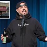 Anthony Krayenhagen, comediante, se apresentando no palco com um microfone e uma garrafa de cerveja.