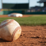 Uma fotografia em close de uma bola de beisebol de couro desgastada apoiada na terra de um campo de beisebol profissional. Comitê do Senado exige que a MLB explique as alegações de jogos de azar após a acusação dos arremessadores