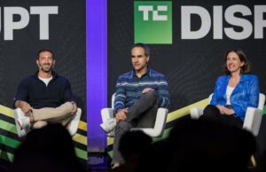 Como a OpenAI e o Google veem a IA mudando as estratégias de entrada no mercado Three speakers talk on a stage with a black backdrop.