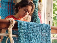 Como os artistas palestinos carregam o espírito de resiliência das Novas Visões Nabil olha diretamente para a câmera, com um cachimbo na boca e na mão esquerda. Atrás dele está uma grande obra de arte em tons terrosos