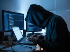 Connecticut alerta sobre esquema DraftKings que leva a prisões em fraude crescente Uma fotografia sombria de uma figura sombria debruçada sobre um laptop brilhante em uma sala mal iluminada, com o rosto parcialmente obscurecido pela luz azul que emana da tela. Connecticut alerta sobre esquema DraftKings que leva a prisões em fraude crescente