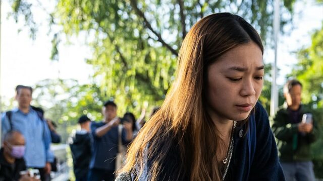 Um enlutado segurando uma flor perto do local para lamentar as vítimas dos incêndios mortais em apartamentos em Hong Kong.