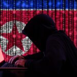 Ilustração de uma figura encapuzada digitando em um laptop com uma bandeira digital da Coreia do Norte ao fundo.