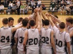 Descobriu-se que seis estudantes atletas manipularam apostas pela NCAA Time de basquete Coopersville Broncos. Um time de basquete de uma escola ou faculdade se reúne na quadra central com as mãos levantadas antes do jogo. Os jogadores vestem camisetas brancas combinando com detalhes escuros, e os espectadores sentam-se nas arquibancadas ao fundo. Descobriu-se que seis estudantes atletas manipularam apostas pela NCAA