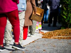 Destinatários SNAP: Confira estes recursos online As pessoas fazem fila segurando caixas de papelão e sacolas de supermercado.