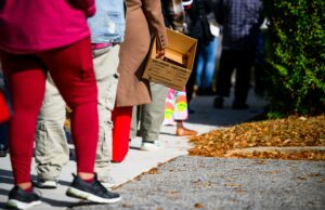 Destinatários SNAP: Confira estes recursos online As pessoas fazem fila segurando caixas de papelão e sacolas de supermercado.