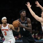 O guarda do Nets, Drake Powell (4), é guardado pelo guarda do New York Knicks, Josh Hart (3) e pelo guard Tyler Kolek (13)