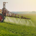 A machine sprays pesticides on a crop field.