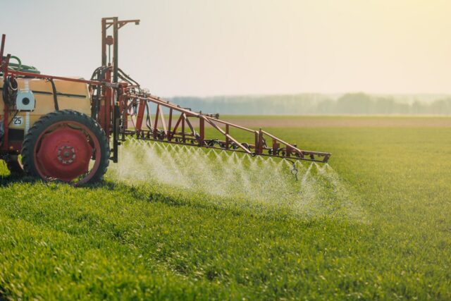 A machine sprays pesticides on a crop field.