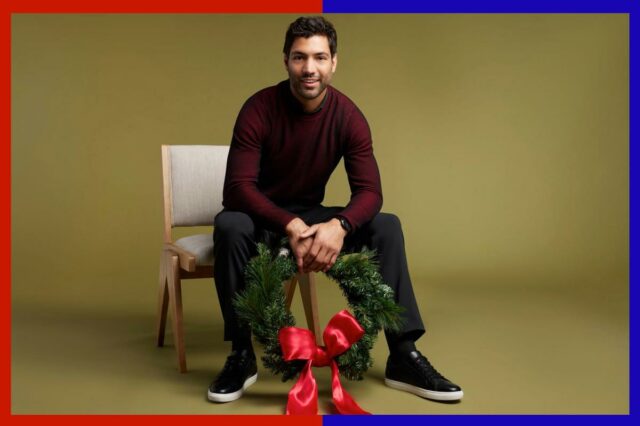 Economize até 70% em ofertas da Men's Wearhouse e tenha Um homem de casaco preto segurando um guarda-chuva preto olha por cima do ombro.