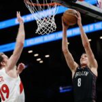 Egor Dëmin tenta enterrar enquanto Jakob Poeltl defende durante a derrota do Nets para o Raptors em 11 de novembro de 2025.