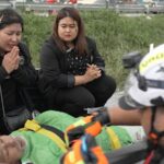 Krongkarn Jantarasavad (à esquerda) orando por seu pai – Damrong Chantarawasat, de 76 anos – que faltou ao tratamento de diálise porque as enchentes o prenderam dentro da casa da família.