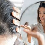 Jovem preocupada olhando no espelho para um monte de cabelo caído na mão.