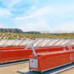 Exowatt's orange P3 units sit on sandy ground near a data center.