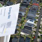 Eletricista não identificado realizando instalação de painel solar no telhado da casa usando chave de fenda sem fio