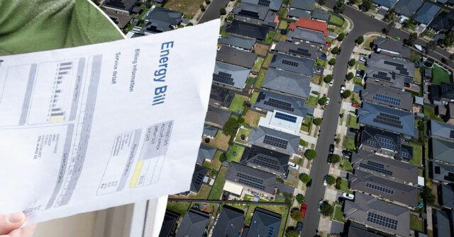 Eletricista não identificado realizando instalação de painel solar no telhado da casa usando chave de fenda sem fio