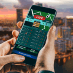 Florida House avalia revisão dos jogos de azar, endurecendo as penalidades e regulamentando os esportes de fantasia. Uma pessoa segurando um smartphone exibindo uma interface de apostas esportivas ao vivo, com o horizonte de uma cidade desfocado ao fundo ao pôr do sol.