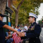 Joesph Ouellette, um oficial veterano da Marinha de 100 anos e comandante da Segunda Guerra Mundial, aperta a mão de Randy Torres, um policial militar veterano do Exército e agora policial de San Jose, durante o 107º desfile anual do Dia dos Veteranos de San Jose no centro de San Jose, em San Jose, Califórnia, na terça-feira, 11 de novembro de 2025. (Shae Hammond/Bay Area News Group)