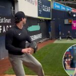 O arremessador do New York Yankees, Gerrit Cole, vestindo uma camiseta e chapéu pretos do Yankees, segurando uma luva preta.