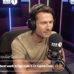 Um homem sentado em uma cabine de rádio usando fones de ouvido.