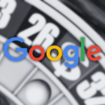 Uma roleta borrada com bolsos numerados em vermelho, preto e verde aparece no fundo, sobreposta ao logotipo multicolorido do Google em foco nítido no centro. Google mira em jogos de sorteio, removendo classificação ‘social’