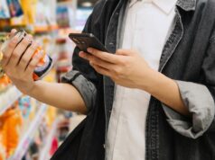 Ingrediente ‘perigoso’ escondido em alimentos nas prateleiras dos supermercados australianos Estudante chinês asiático olhando para smartphone enquanto escolhe itens no supermercado.