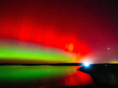 Isso acontecerá de novo? Por que a previsão da aurora boreal está mudando. Um carro cruza a represa Hulah sob o brilho da aurora boreal em 11 de novembro de 2025, durante um raro avistamento de aurora no norte de Oklahoma.