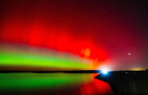 Isso acontecerá de novo? Por que a previsão da aurora boreal está mudando. Um carro cruza a represa Hulah sob o brilho da aurora boreal em 11 de novembro de 2025, durante um raro avistamento de aurora no norte de Oklahoma.