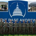 Oito cadetes da USAFA uniformizados posam em frente a uma placa azul da Base Conjunta Andrews.