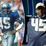 Kenny Easley, vestindo uma camisa do Seattle Seahawks com o número 45, levanta os braços em comemoração.