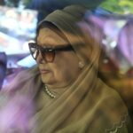 Ativistas em apoio à ex-primeira-ministra de Bangladesh, Khaleda Zia, seguram uma faixa com seu retrato enquanto rezam por sua recuperação em frente ao Hospital Evercare, em Dhaka, em 29 de novembro de 2025.