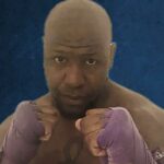 Um homem musculoso com mão roxa em posição de luta.