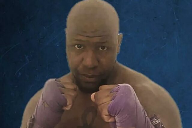 Um homem musculoso com mão roxa em posição de luta.