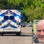 Foto de um homem careca sorridente com cavanhaque, vestindo uma camisa xadrez e um brinco.