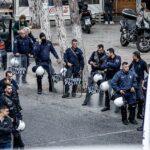 Uma mulher de 56 anos foi uma das duas pessoas mortas a tiros durante um dramático tiroteio em uma vila nas montanhas de Creta no sábado. Na foto: Policiais armados montam guarda após o incidente