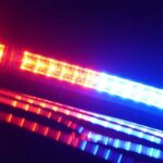 Um close de uma barra de luz de carro de polícia, com luzes de emergência vermelhas e azuis piscando.