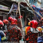 O pessoal dos bombeiros trabalha no local depois que pelo menos três pessoas morreram no local quando a grade do telhado de um prédio de cinco andares desabou após um terremoto na área de Kosaituli, em Armanitola, em Dhaka, Bangladesh, em 21 de novembro de 2025.