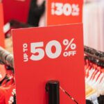 Sinais de desconto vermelhos em cabideiros em uma loja de roupas.