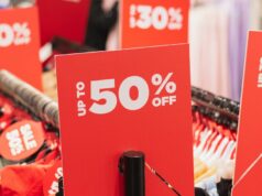 Negócios duvidosos abundam nas vendas da Black Friday – veja como identificá-los Sinais de desconto vermelhos em cabideiros em uma loja de roupas.