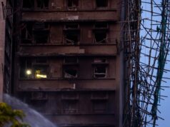 Número de mortos em incêndios em Hong Kong sobe para 83 enquanto equipes de resgate usam tochas para vasculhar torres queimadas Um bombeiro vasculha um prédio.